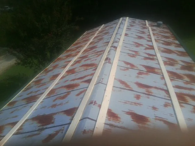 Rusted metal roof panels with new wood purlins before replacement — Storm Damage Roof Repair in Crossville by Roofing Brothers
