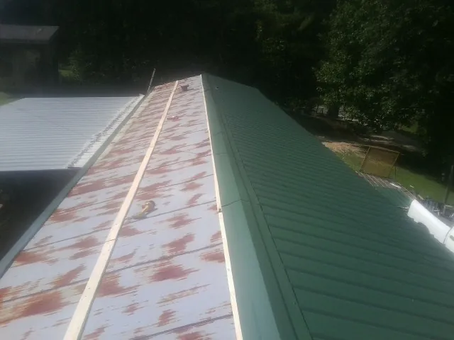 Old rusted panels beside newly installed green metal roofing — Wind Damage Roof Repair by Roofing Brothers in Crossville