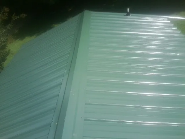 New green metal panels meeting at the ridge of a roof — Flat Roof Repair work by our crew in Crossville
