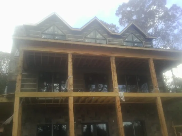 Dormers and porch framing on a large log home under construction — Roof Coating work by our crew in Crossville