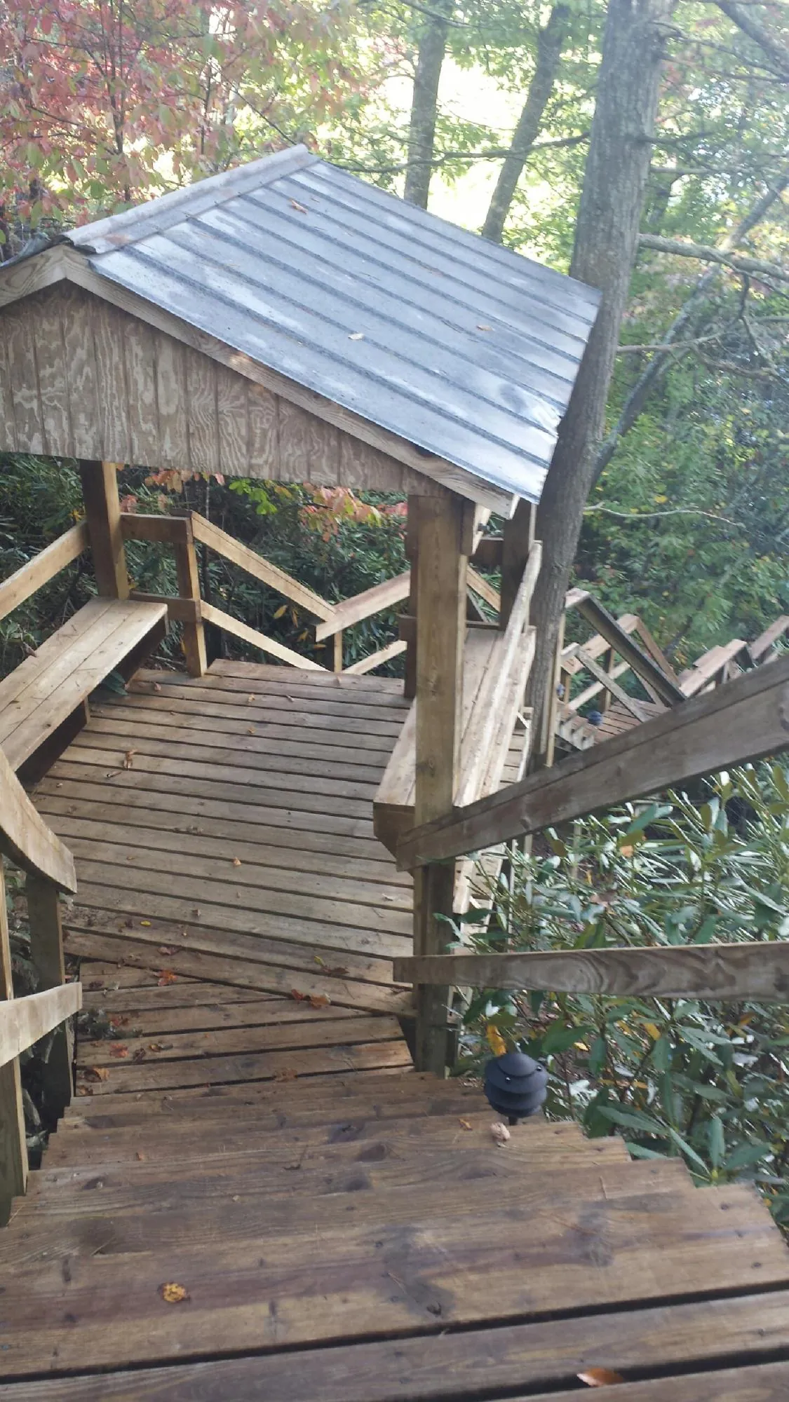 Metal roofed shelter over wooden steps on a wooded walkway — Skylight Repair & Installation work by our crew in Crossville