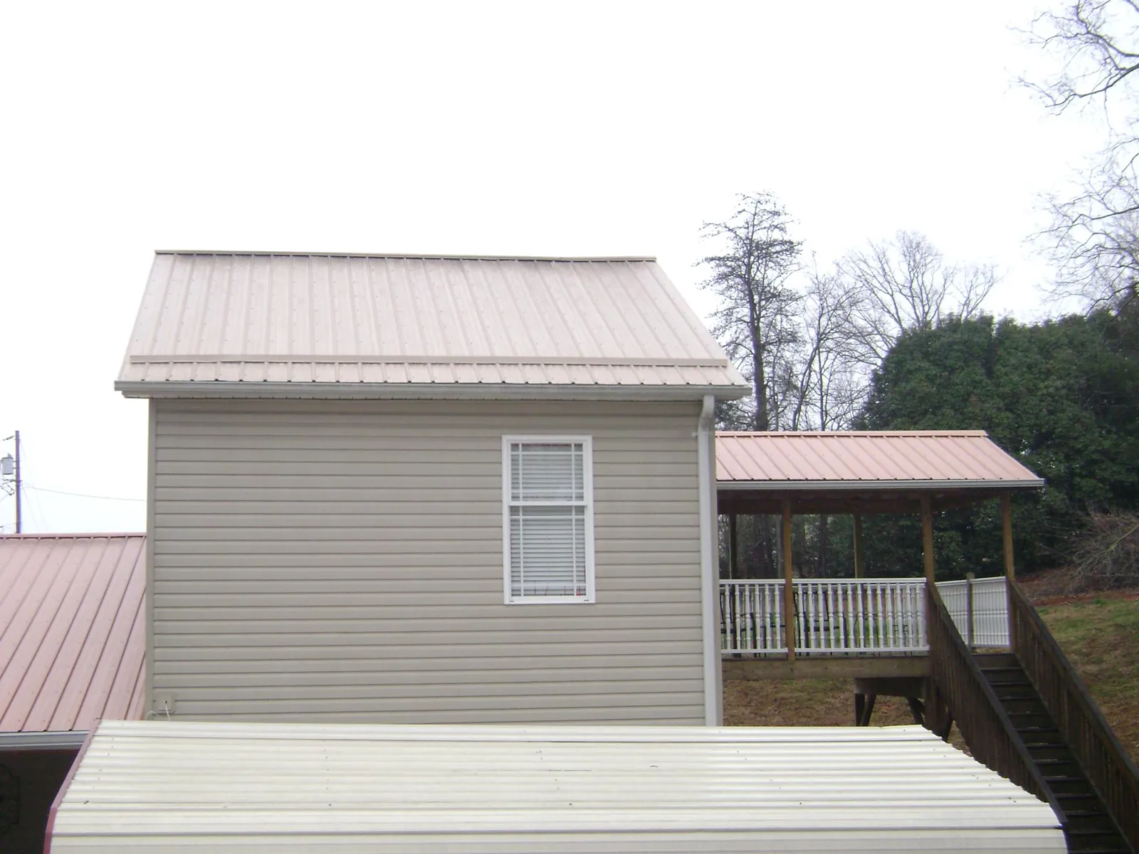 Tan metal roofs on a two story addition and attached porch, from a Roof Replacement job in Crossville