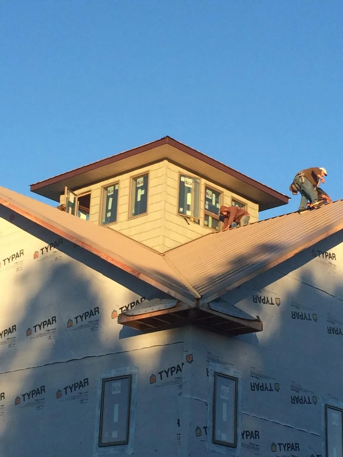 Roofers working around a rooftop cupola on a new metal roof at sunset — Roof Waterproofing in Crossville by Roofing Brothers
